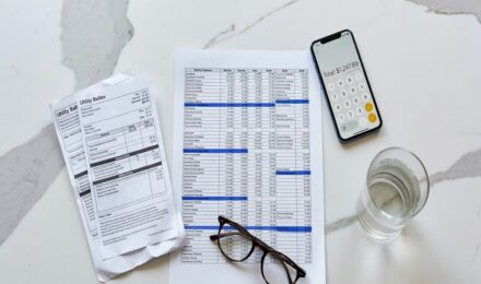 Overhead view of a household budget with insurance costs highlighted alongside bills and a calculator