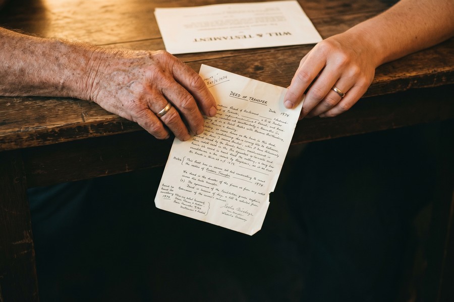 A 45-year-old man reviewing and signing life insurance policy documents at a desk