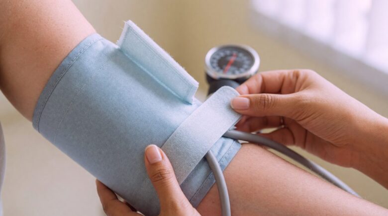 Paramedical examiner taking blood pressure reading during term life insurance medical exam