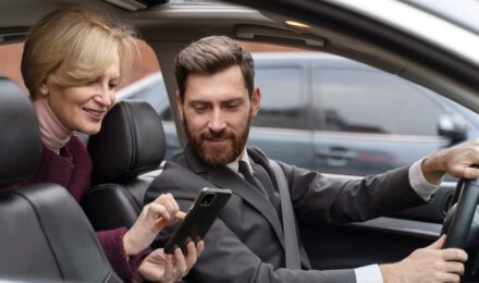 Rideshare driver checking phone with car dashboard visible, illustrating the insurance gap between personal and commercial coverage