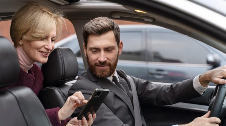 Rideshare driver checking phone with car dashboard visible, illustrating the insurance gap between personal and commercial coverage