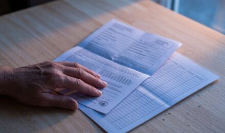 Single parent at desk reviewing insurance documents and bills with calculator