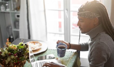Young self-employed freelancer working at home desk with laptop, researching term life insurance options