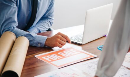 Freelance graphic designer reviewing contract and liability insurance documents at desk in Austin office